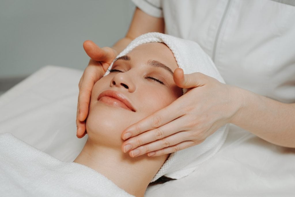 Happy woman getting facial at spa.