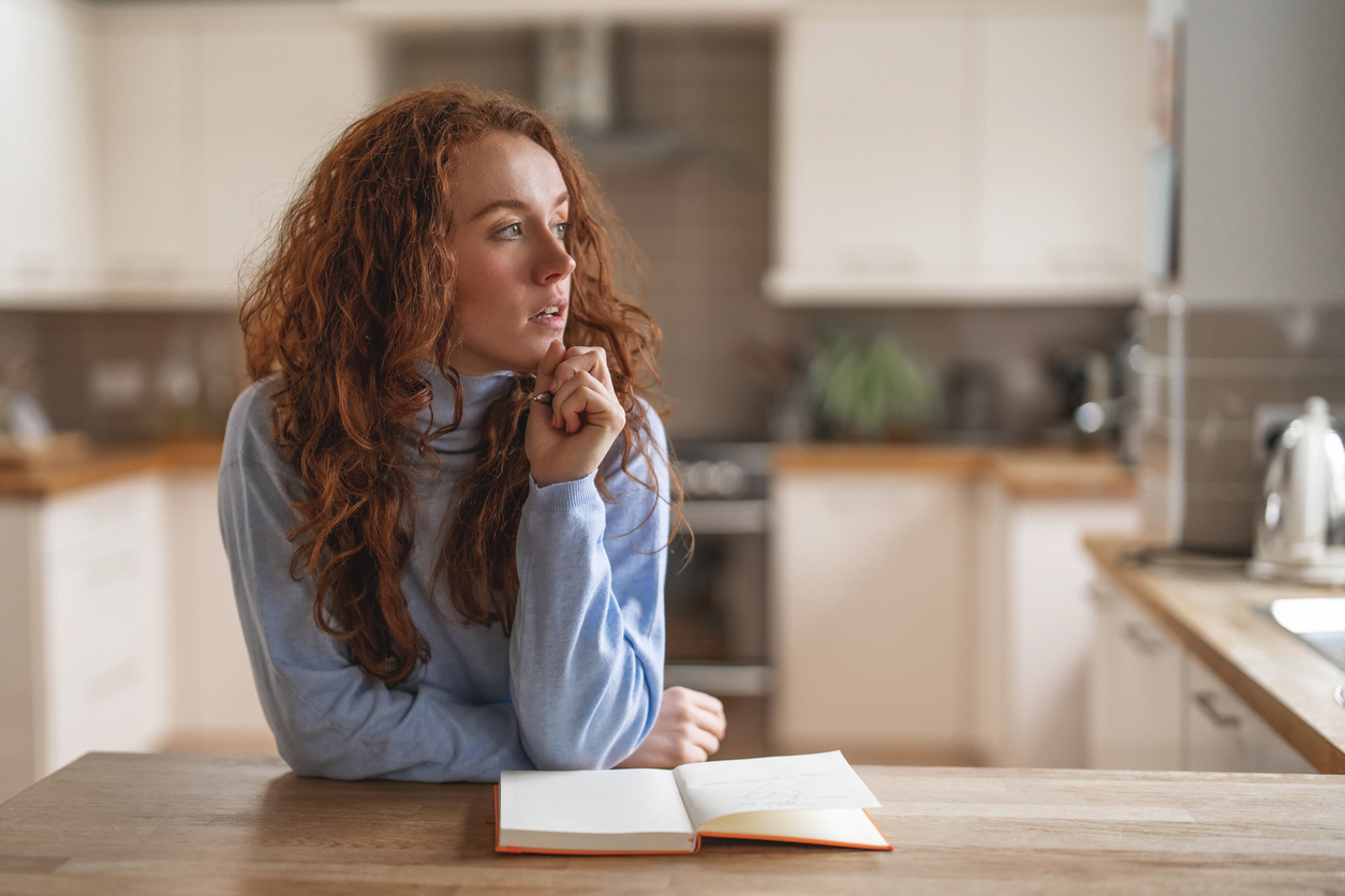 Woman sitting at a kitchen table looking tired and thoughtful in January.
