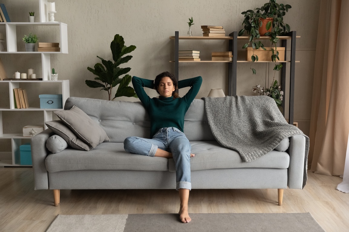 Woman relaxing on a couch at home, representing post-holiday wellness and recovery.